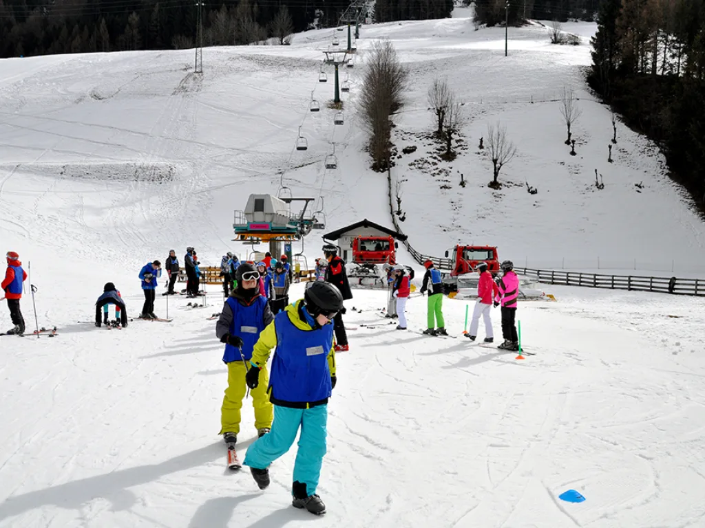 Zwei Jugendliche gehen mit Skiern über die Piste.